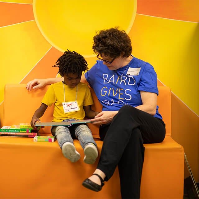 Baird associate sitting with a child reading a book.