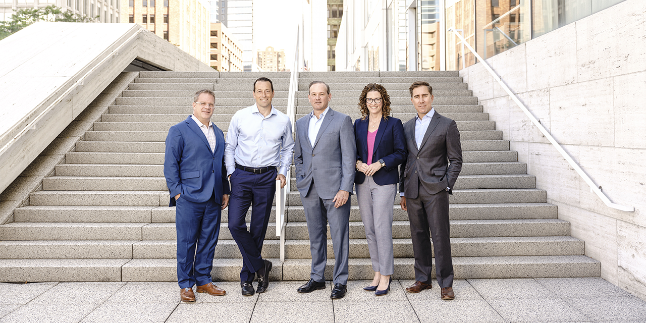Group photo of the leadership for Baird Private Wealth Management standing in front of steps outdoors