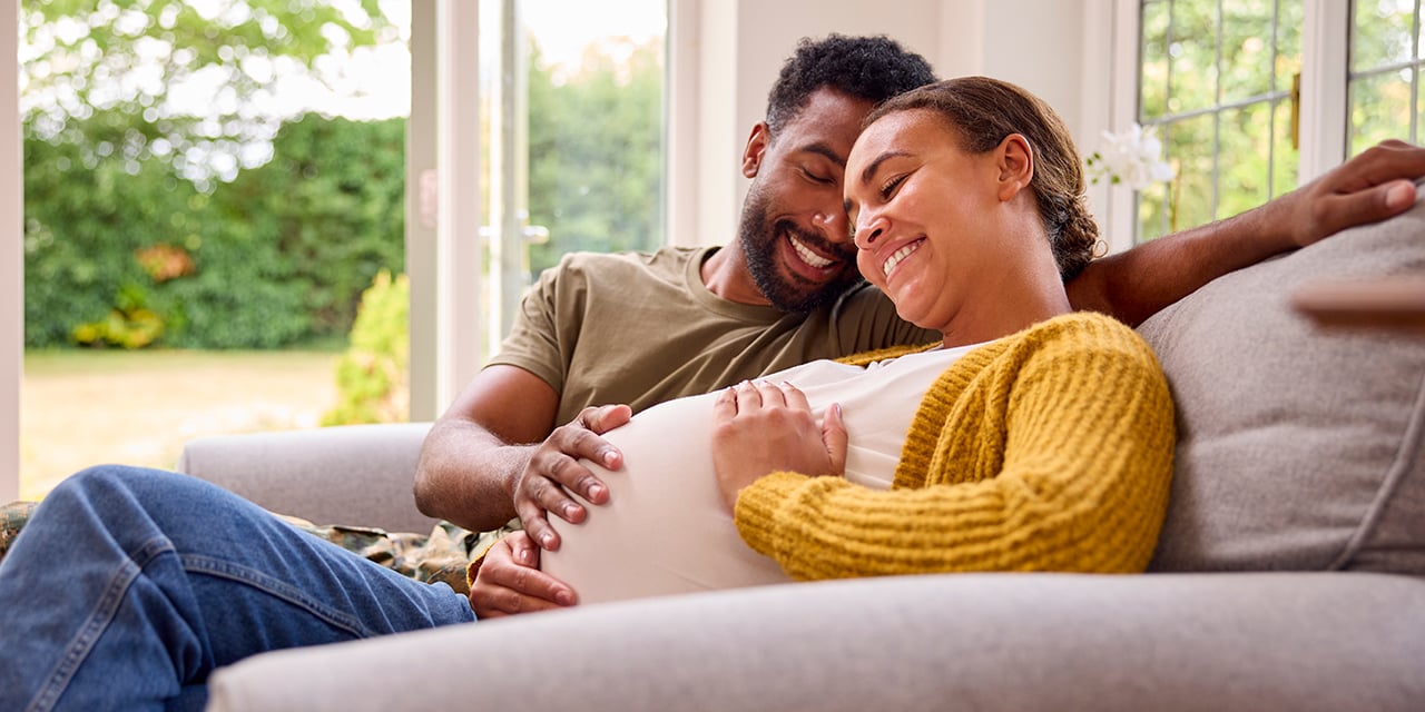 Expectant couple sitting on couch.