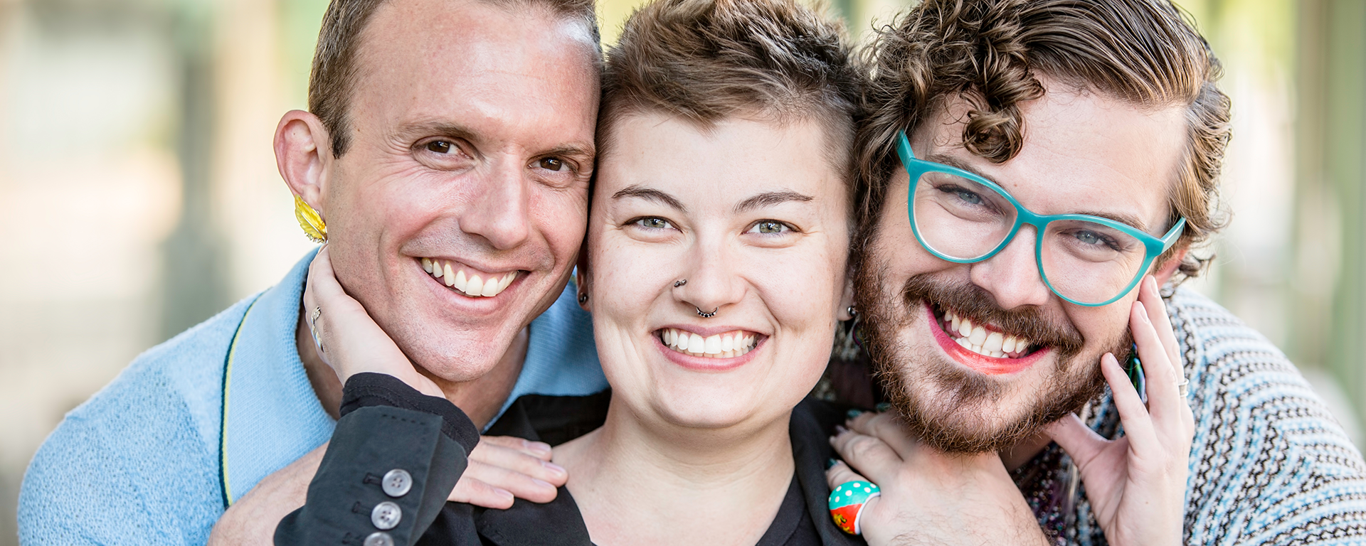 Three gender fluid friends pose and smile for photo.