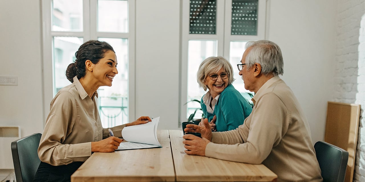 Elderly couple sitting at a table talking to a financial planner.