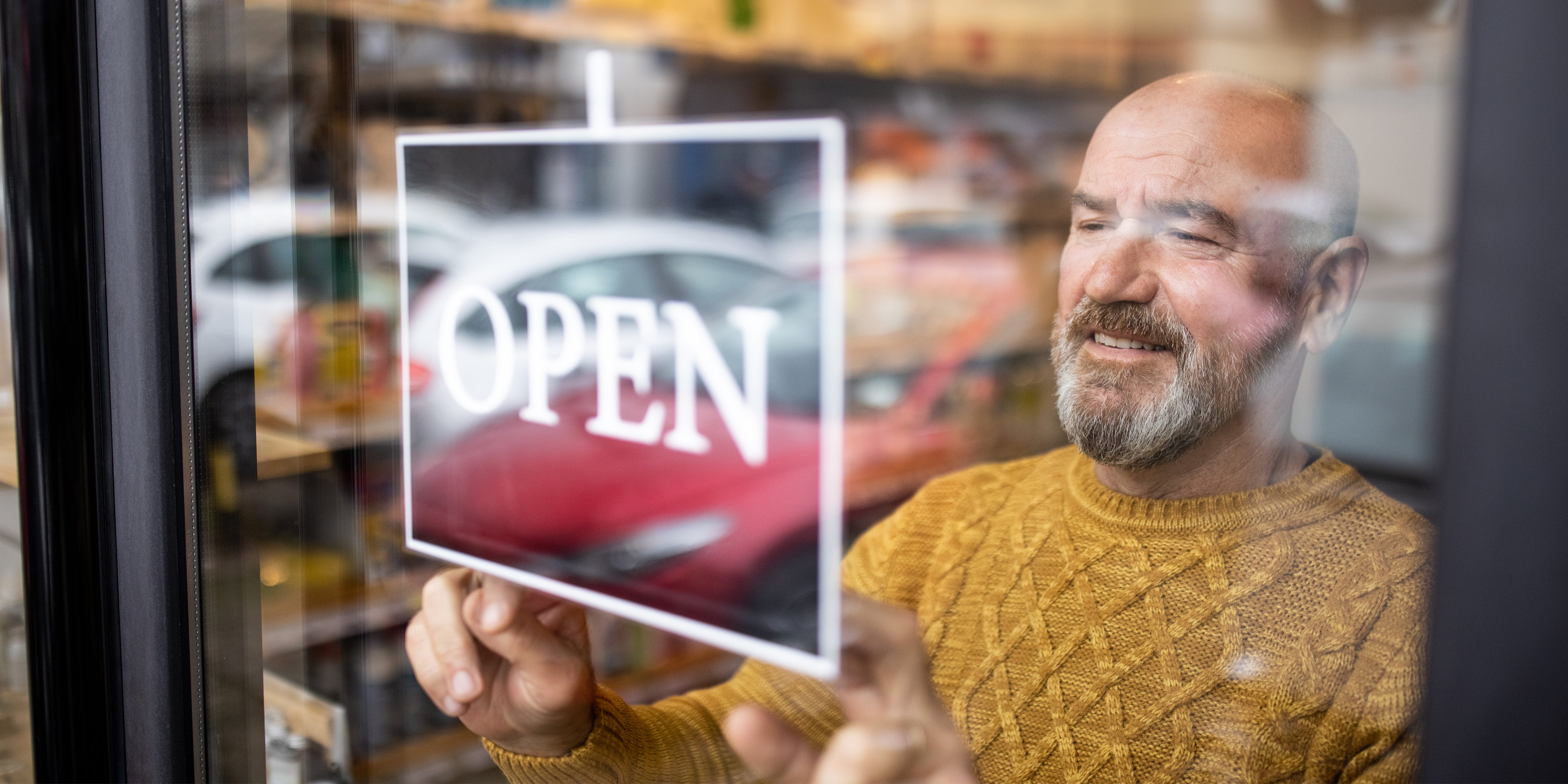 Man placing open sign in window.