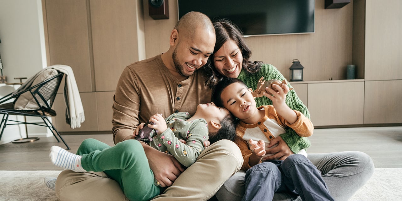 Family sitting together on the floor laughing.