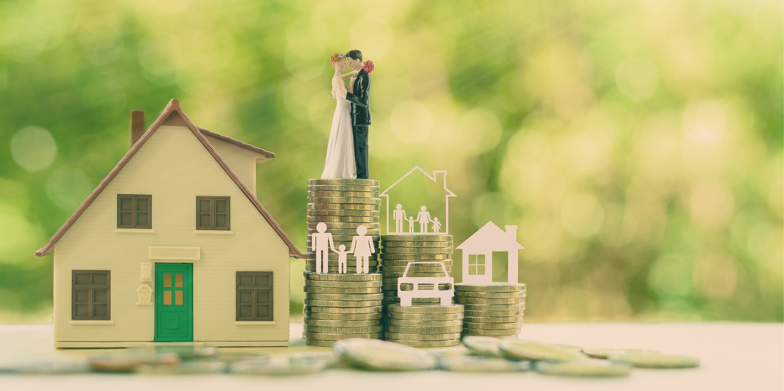 Figures of a bride and groom standing on a stack of coins next to a house