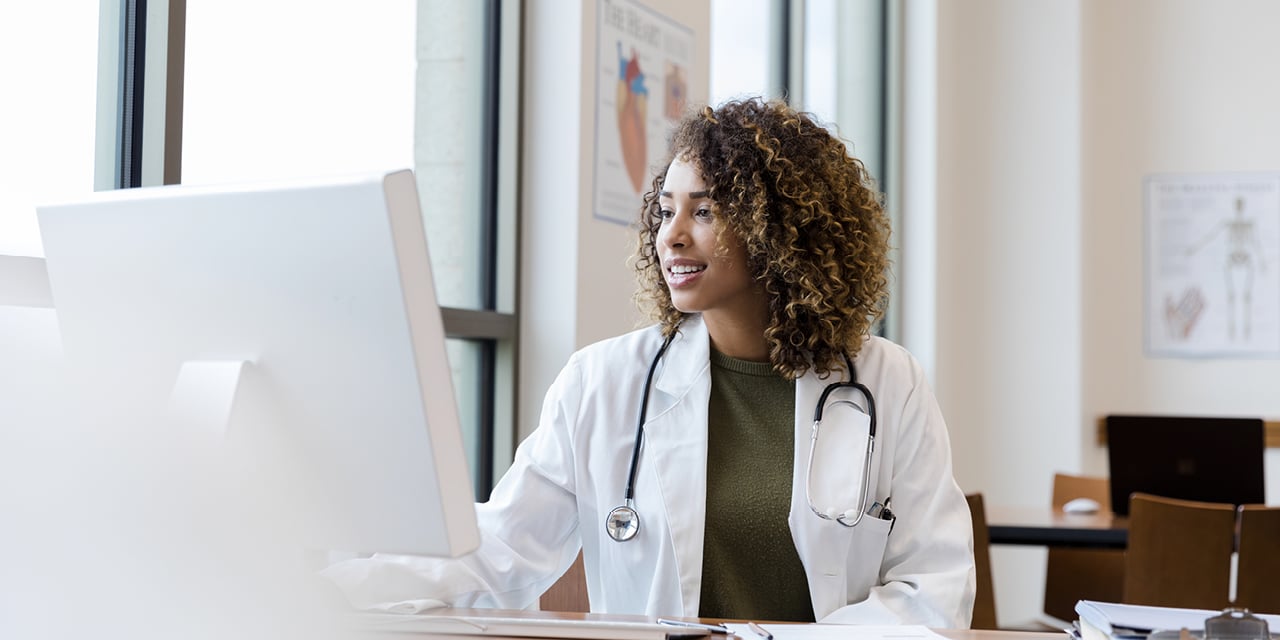 Female physician wearing a lab coat and working on a computer