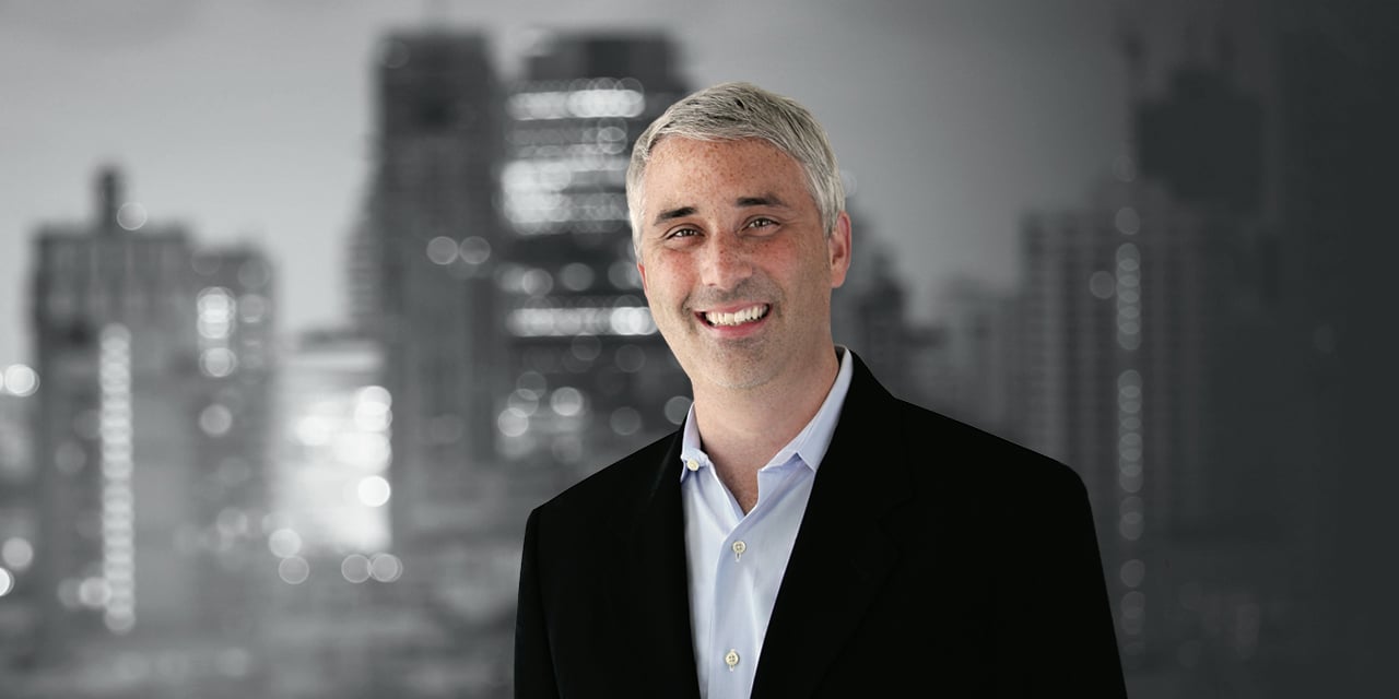 Mike Antonelli stands in front of a black and white cityscape