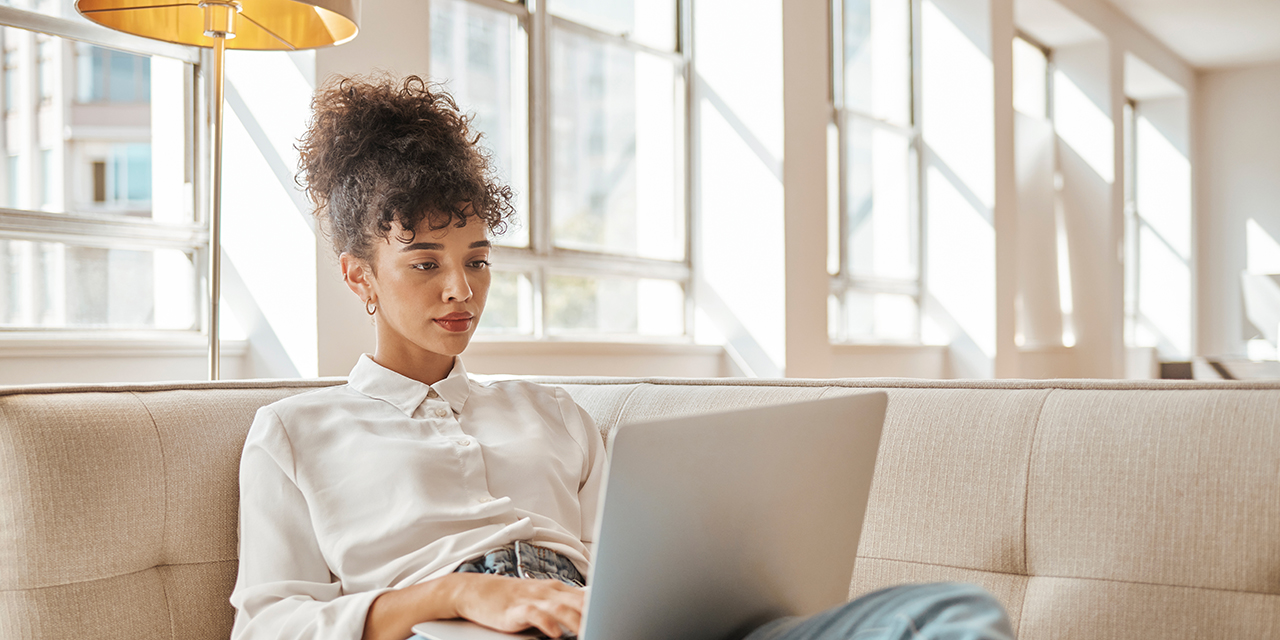 Woman sitting on couch using a laptop.