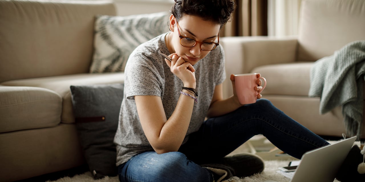 Young adult sitting on the floor doing research.