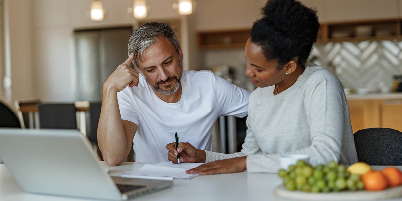 Couple sitting at kitchen table reviewing paperwork.