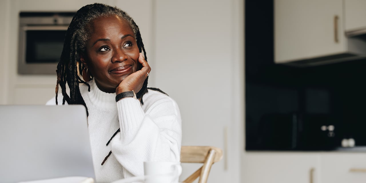 Mature woman looking away thoughtfully while sitting at a desk