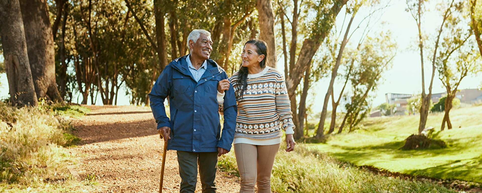 Elderly couple walking on a path in the woods.