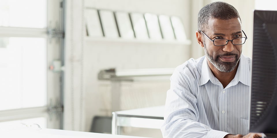 Middle-aged man looking at a computer screen in an office.