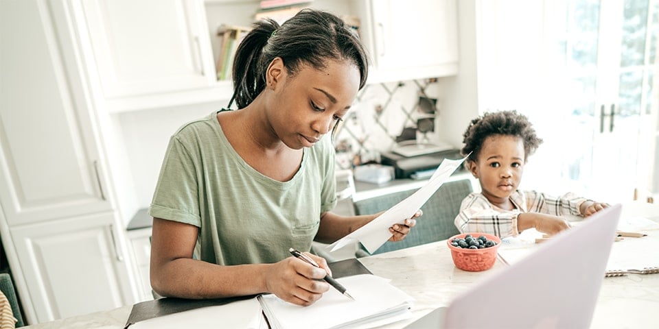Woman sitting at counter going over documents with young child next to her.