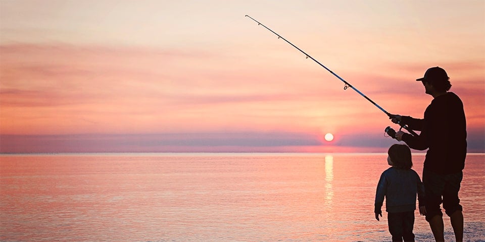 Parent and child fishing at sunset.