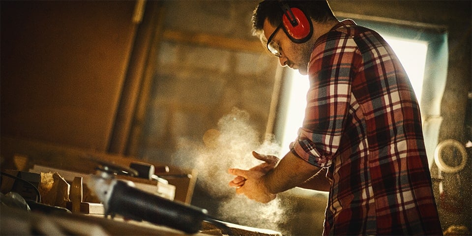 Male wearing protective head and eye gear while wood-working.