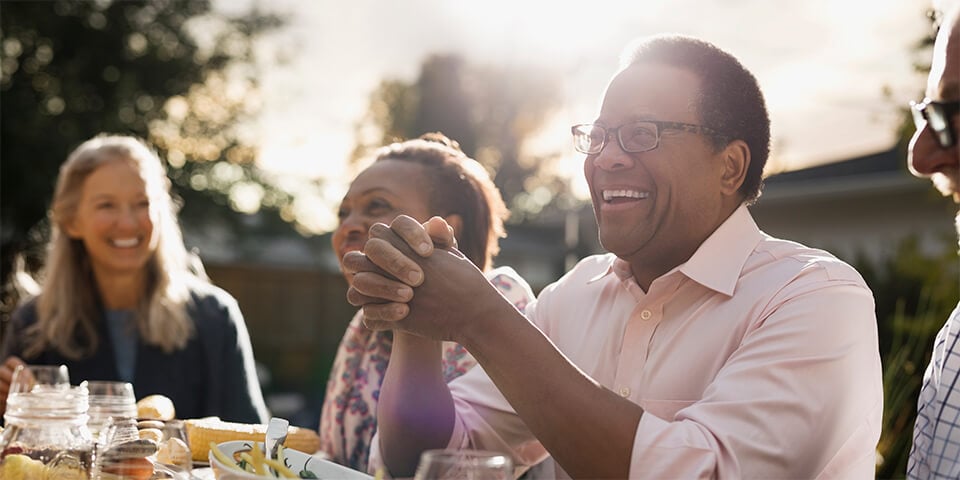 Smiling group of middle-aged people gathered at table setting.