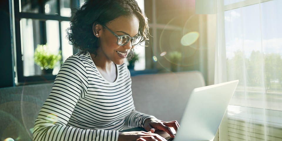 Smiling woman working on silver laptop.