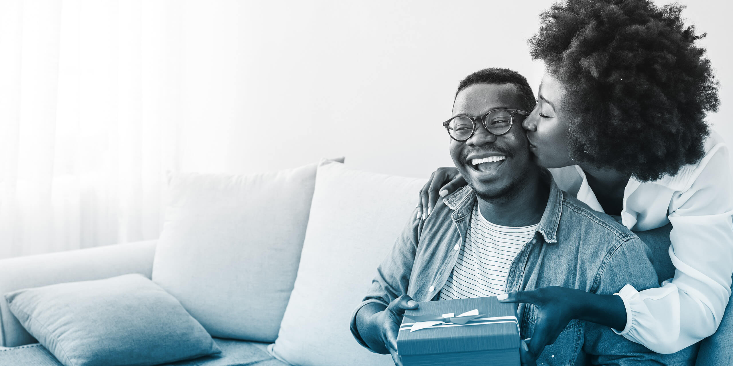 Couple with gift box hugging at home