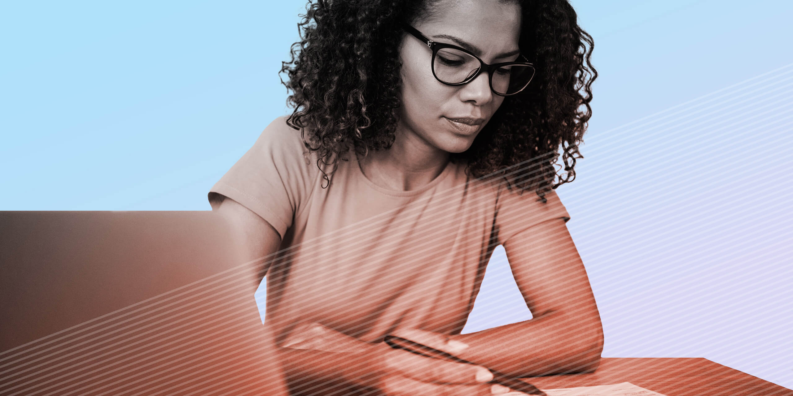 Woman using laptop and making notes on a clipboard