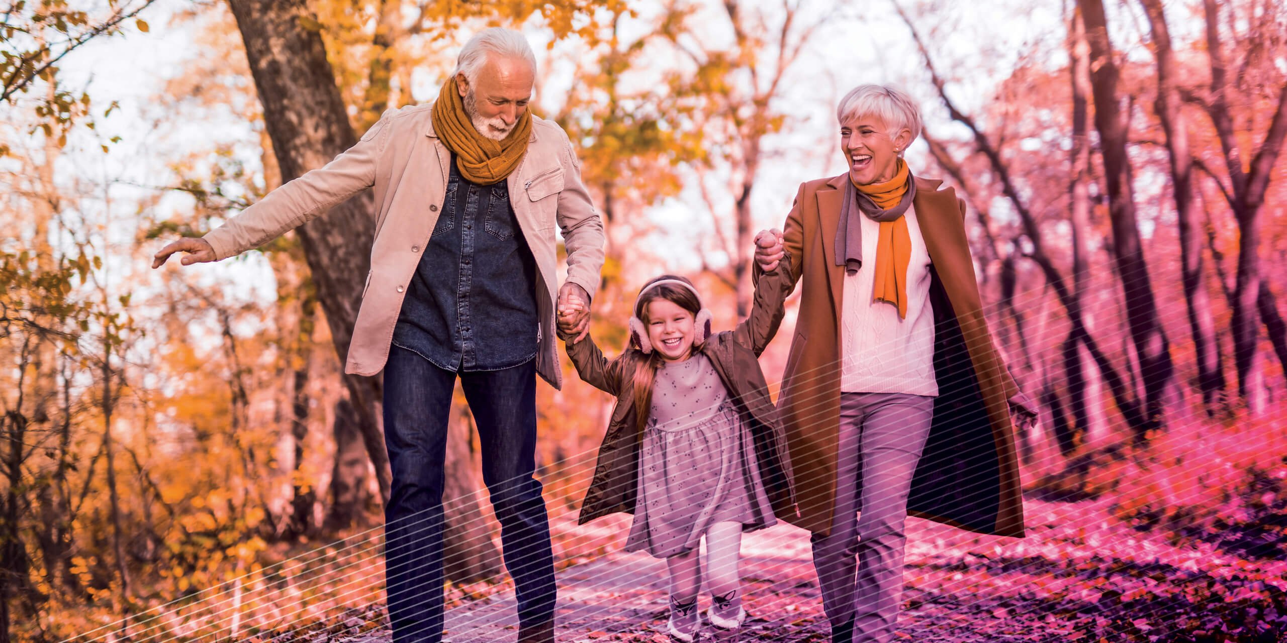 Grandparents holding hands with granddaughter walking down a path