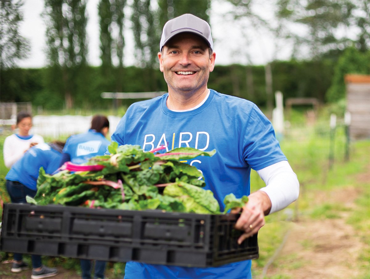 A Baird associate carries a box of greens at a volunteer event
